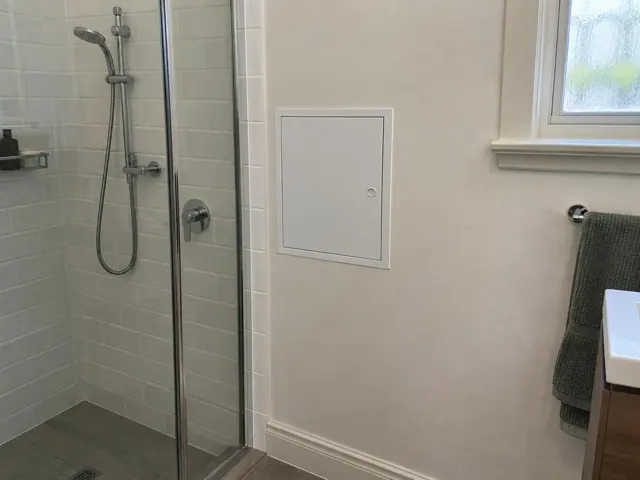 Neat access panel on a bathroom wall beside a shower and window in Kogarah